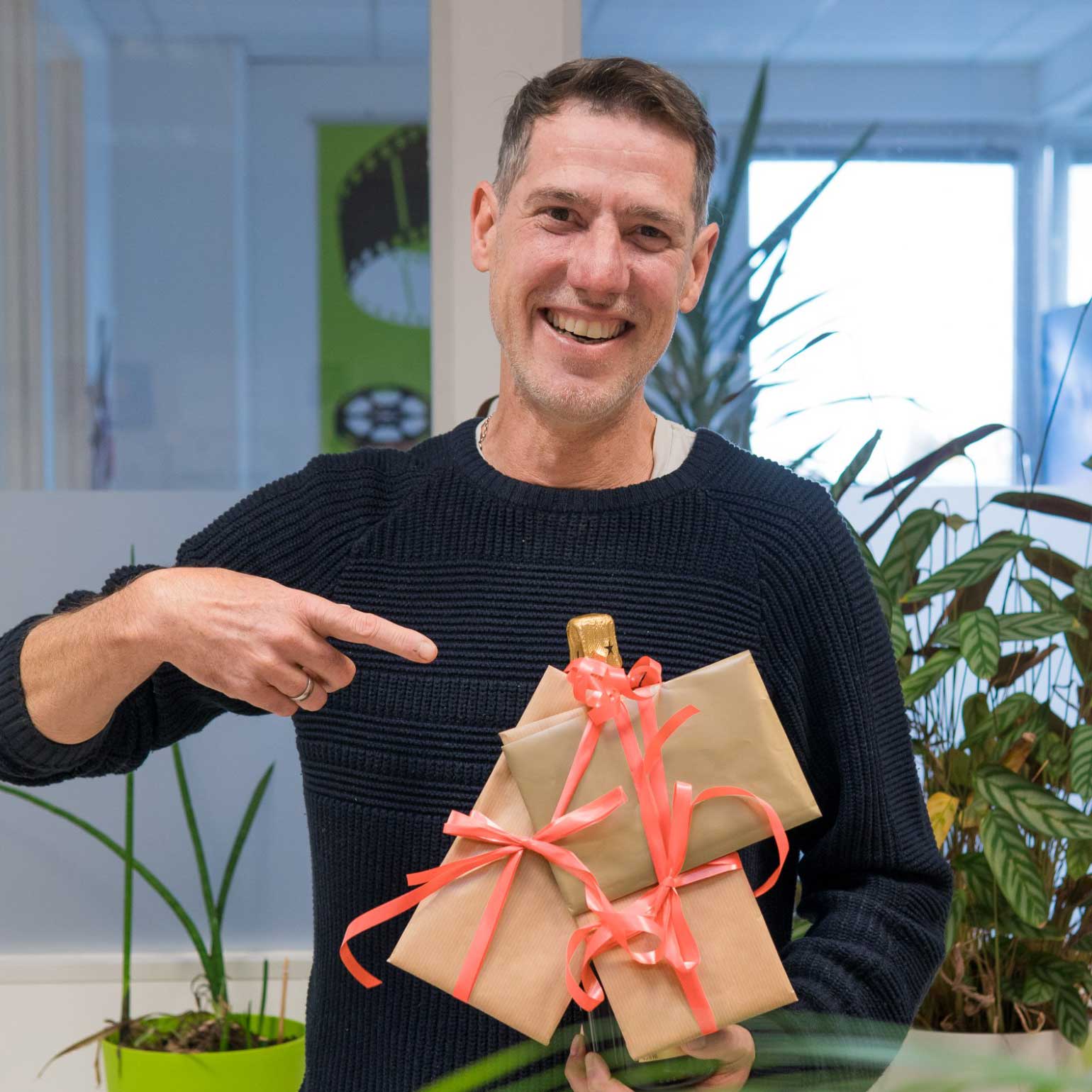 Unser Chefredakteur mit breitem Lächeln und Geschenken in der Hand